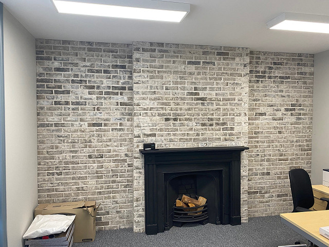 Grey Brick Slips on a black fire place in an office.