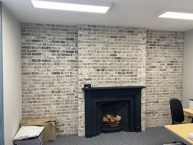 Grey Brick Slips on a black fire place in an office.