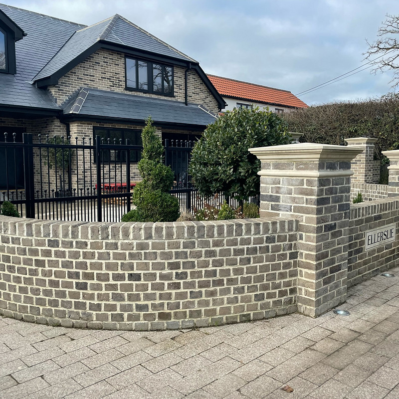 New build house in a soft mud grey brick with a curved wall.