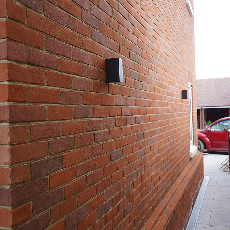 Close-up of a red brick wall with alternating shades of red and brown bricks, evenly spaced with light tan mortar.