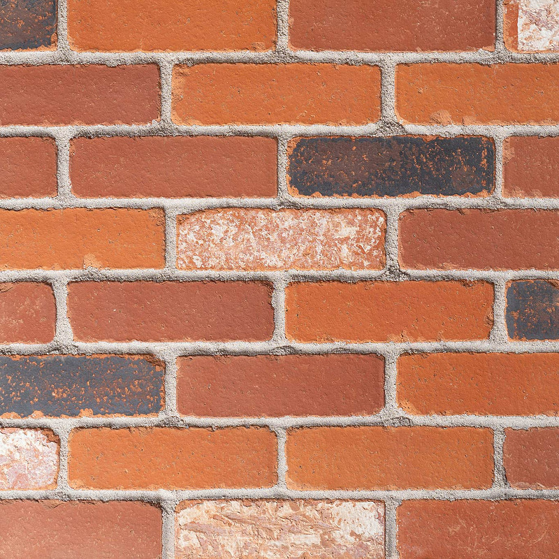 Close up of a rustic tumbled red multi brick.