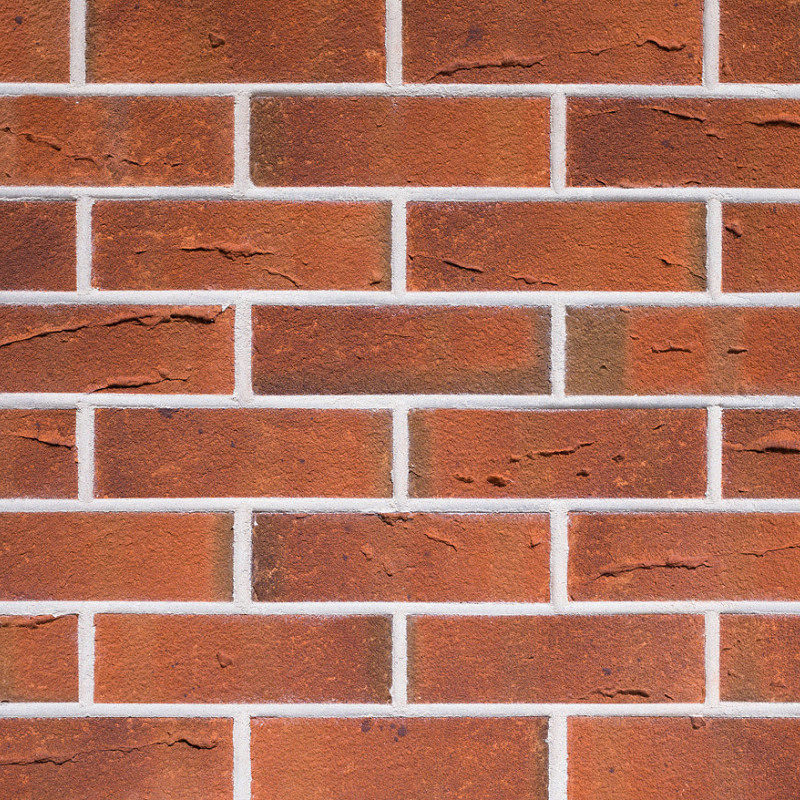 Close-up of red wirecut brickwork with white mortar joints.