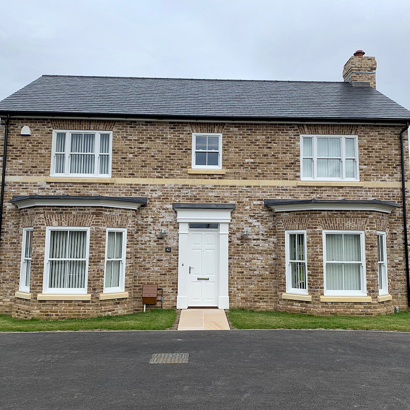 house constructed with a buff facing brick and cast stone features.